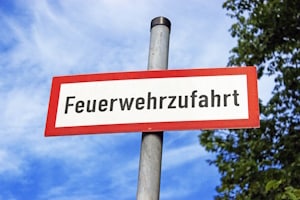 Das rot-weiße Schild mit der Aufschrift "Feuerwehrzufahrt" ist genormt nach DIN 4066.